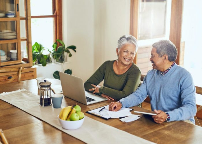 An older woman using a laptop with her husband